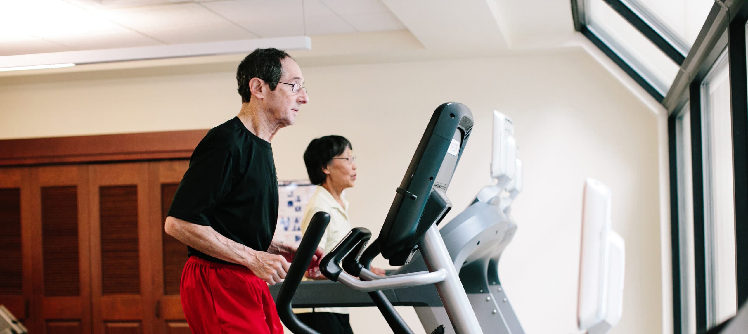A man and woman exercise on the treadmill