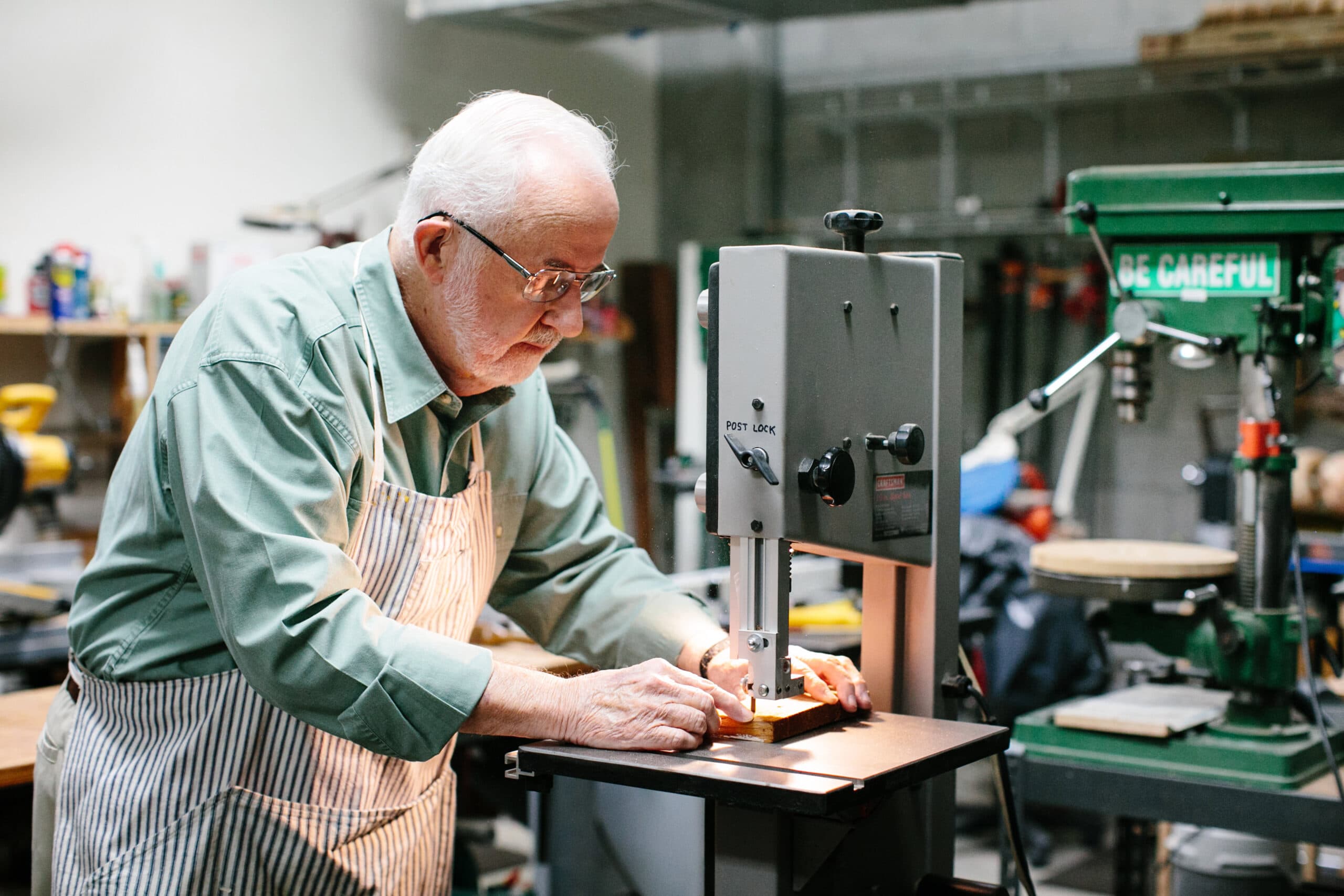 An older man makes a precise cut with a woodworking machine