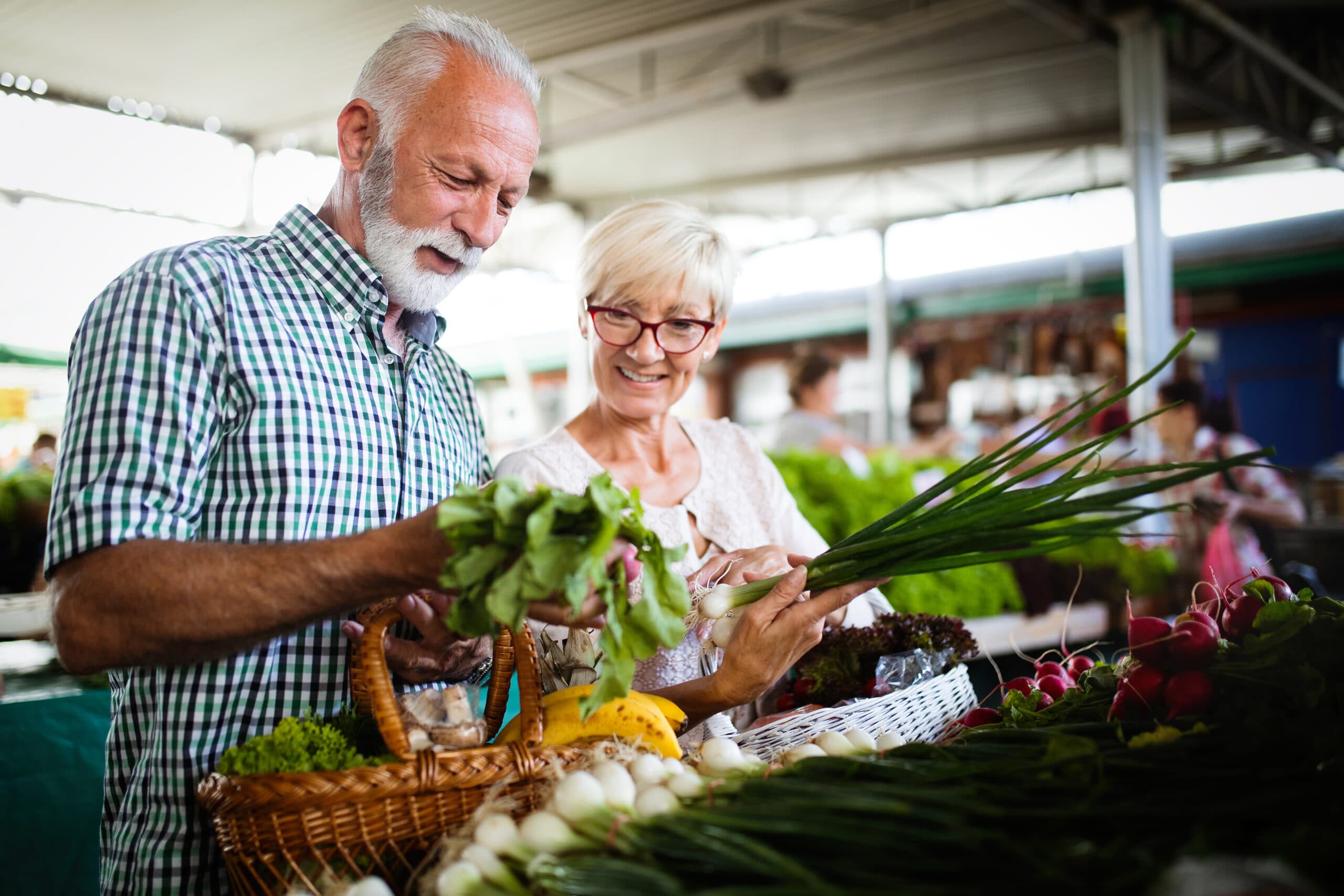 Older couple examines fruits and vegetables at a farmers' market